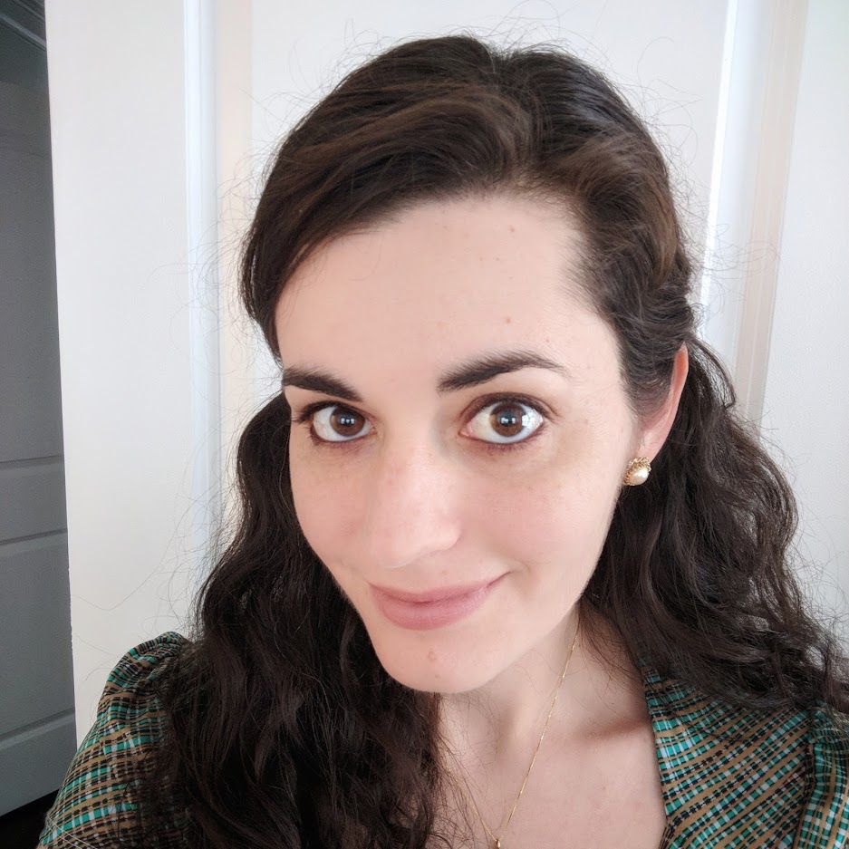 Headshot of julia ferraioli, a white woman with wavy brown hair, against the backdrop of a door